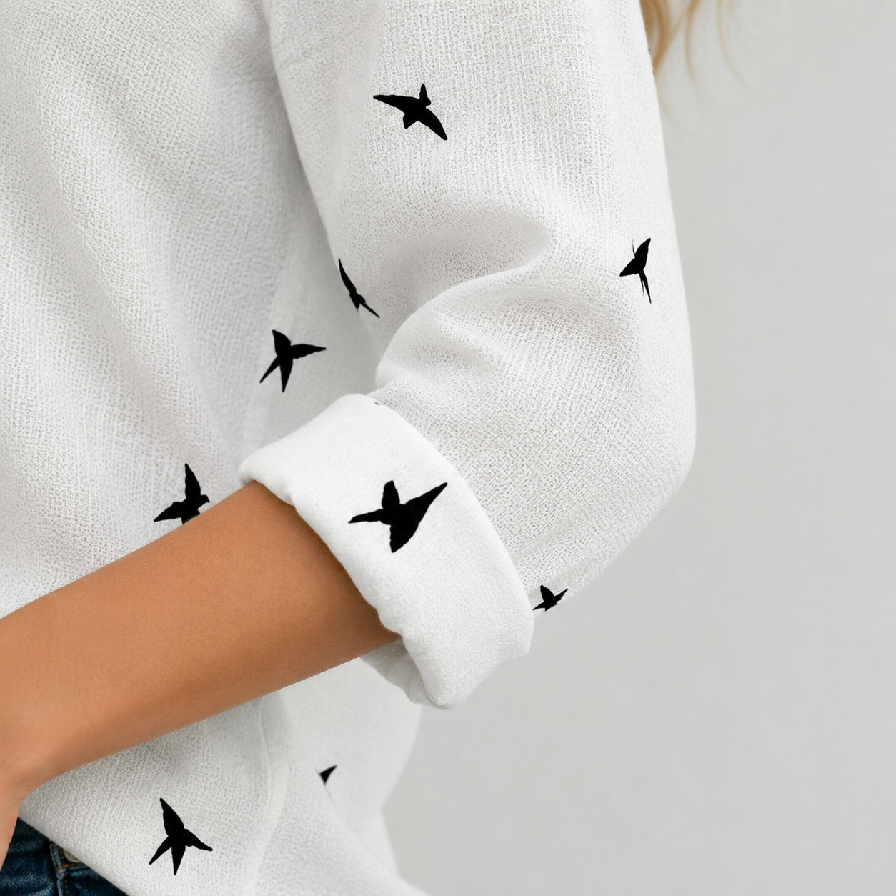Gros plan manche retroussée de blouse blanche imprimé oiseaux